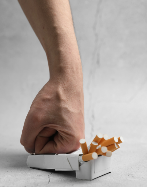 Poing écrasant un paquet de cigarettes, accompagnement à l’arrêt du tabac