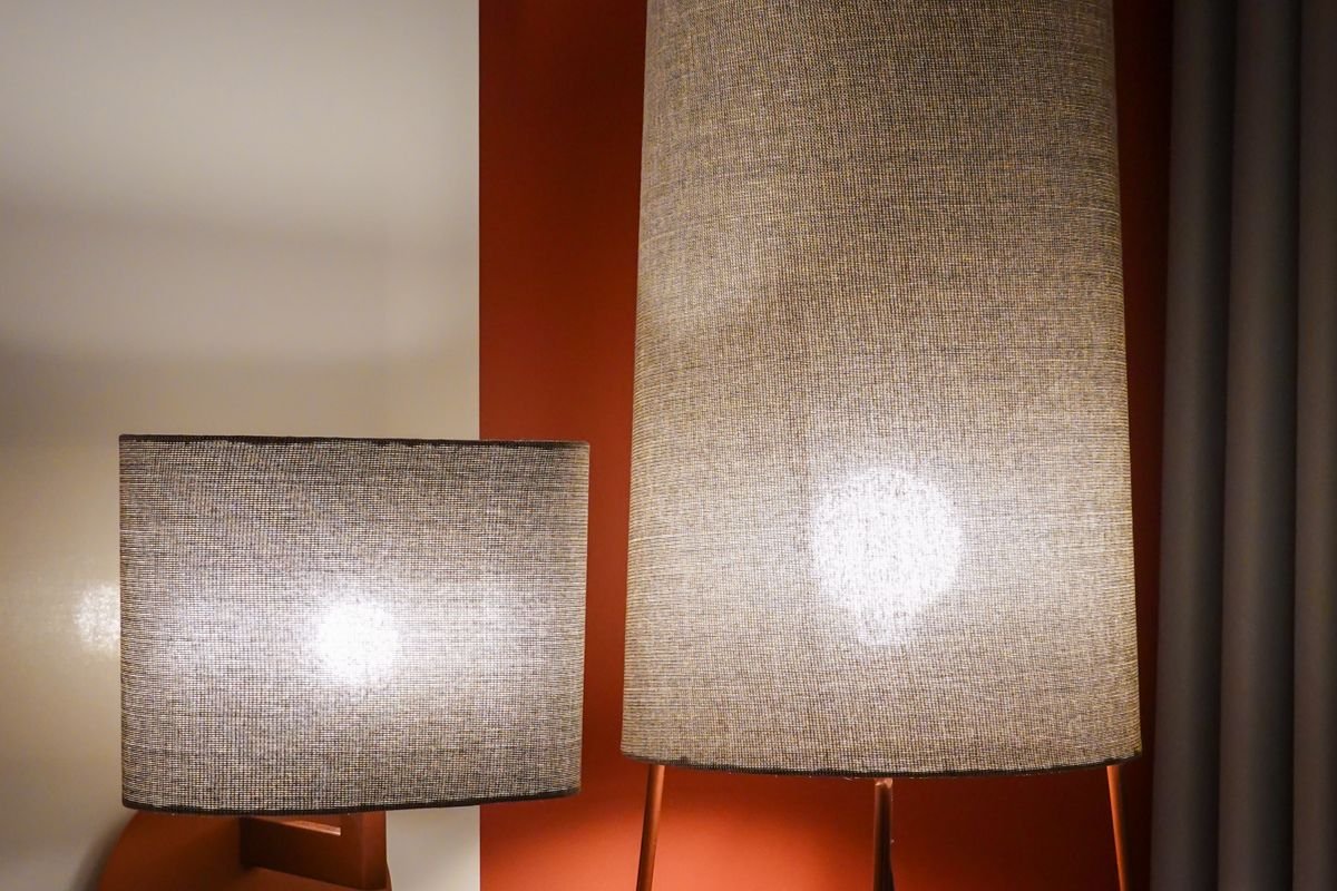Lampe allumée contre un mur clair dans une pièce sobre